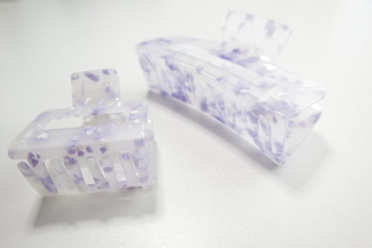 Two clear hair clips with purple floral patterns on a white background