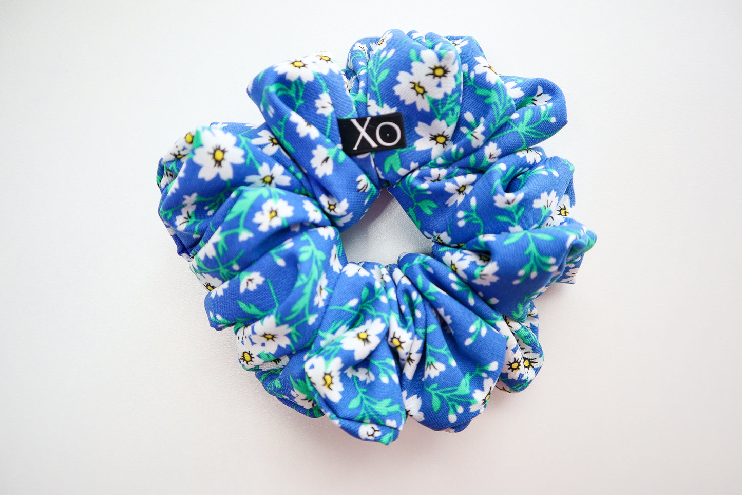 Blue floral scrunchie with 'Xo' logo on a white background. Nora Oversized Scrunchie – true royal blue color in this photo.