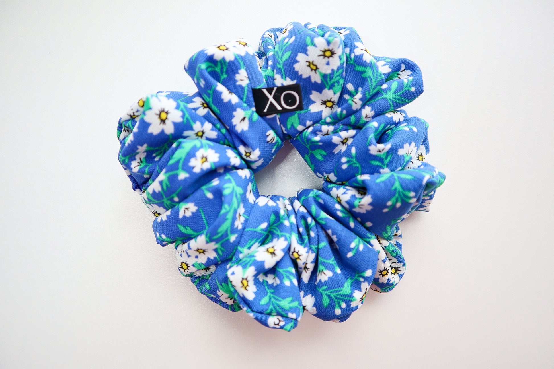 Blue floral scrunchie with 'Xo' logo on a white background. Nora Oversized Scrunchie – true royal blue color in this photo.