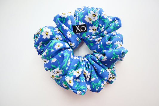 Blue floral scrunchie with 'Xo' logo on a white background. Nora Oversized Scrunchie – true royal blue color in this photo.