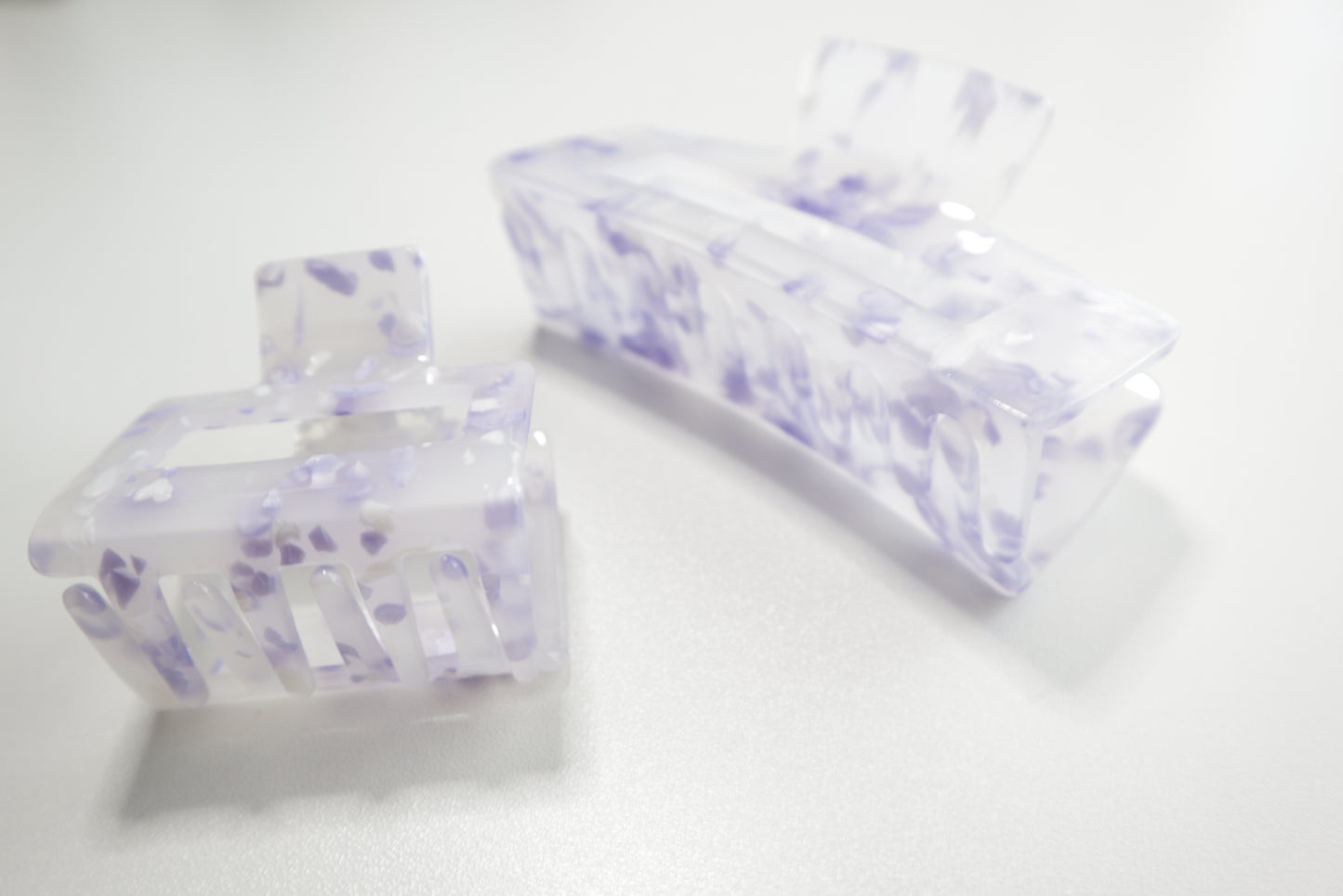 Two clear hair clips with purple floral patterns on a white background