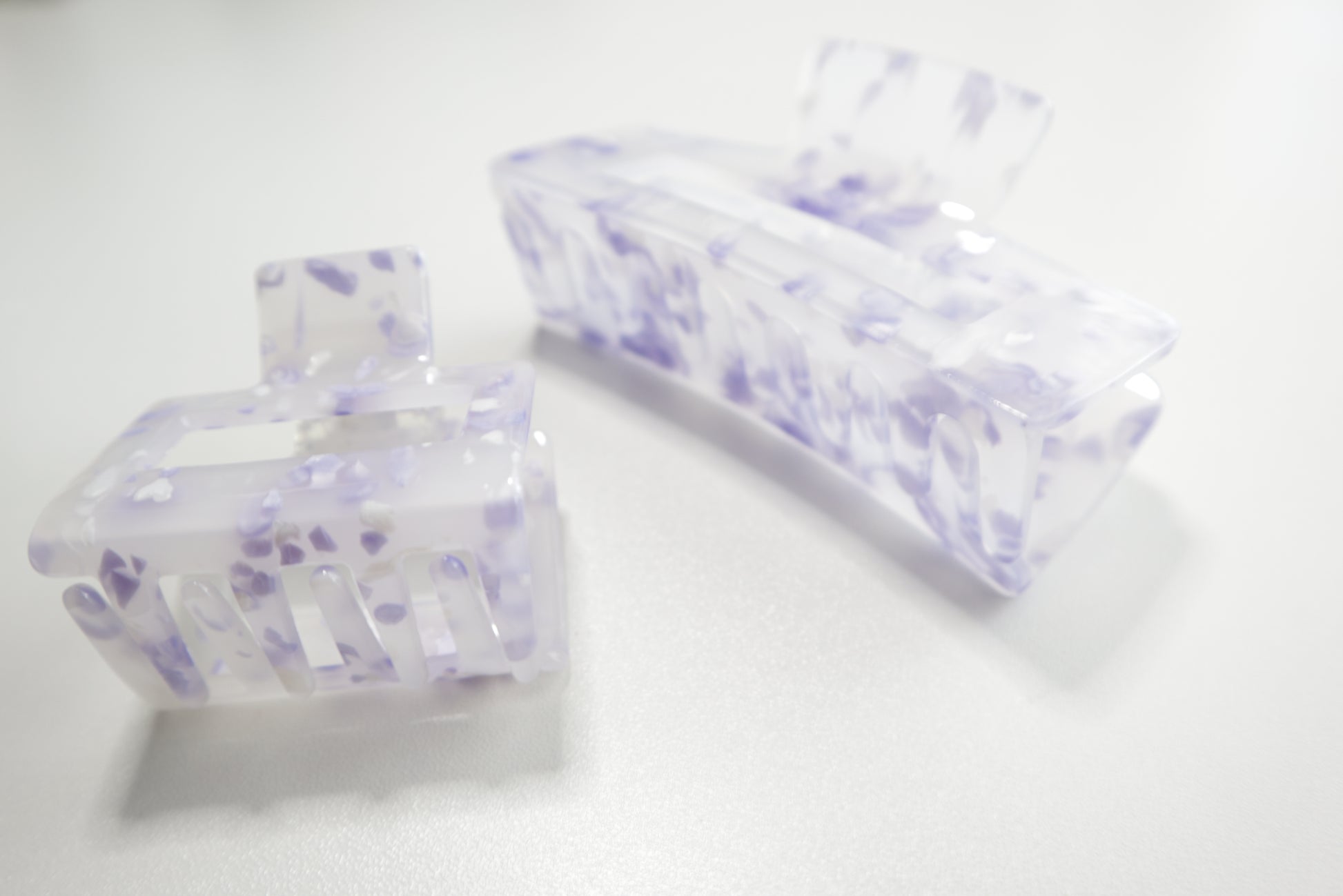 Two clear hair clips with purple floral patterns on a white background