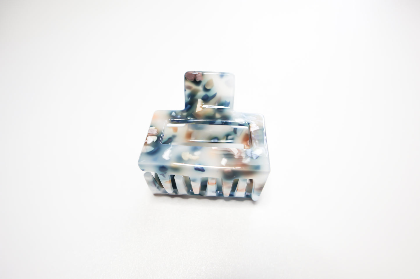 Hair claw clip with blue and brown marble pattern on a white background