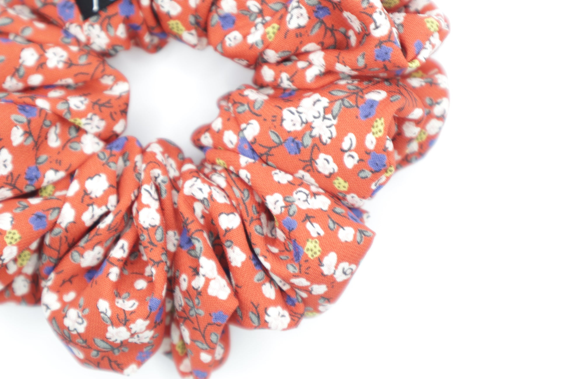 Red floral scrunchie on a white background. Fabric in this photo is less bright due to lighting.