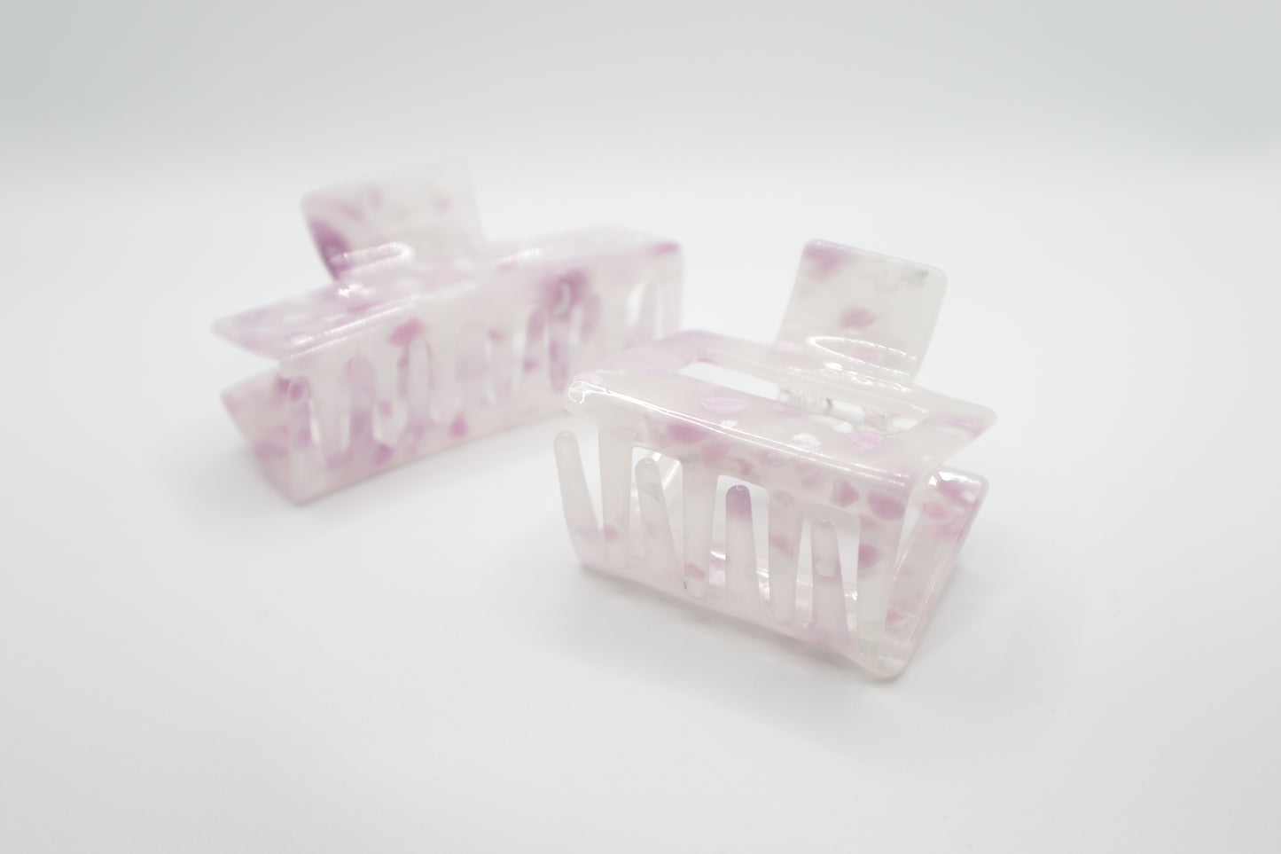 two small hair claw clips in 4" and 2" variants with pink and white marbled pattern on a white background
